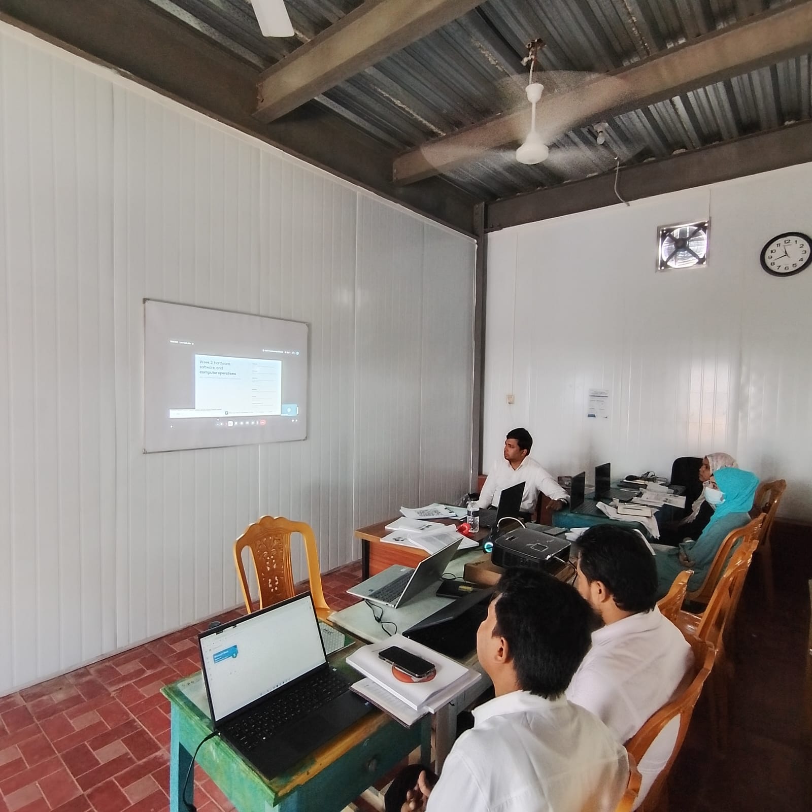 Instructor leading a computer skills lesson with students and laptops